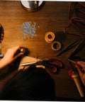 Person using 100Pcs Eyeglass Repair Screws Kit For Quick Eyewear Fixes on wooden desk with tools and small screws
