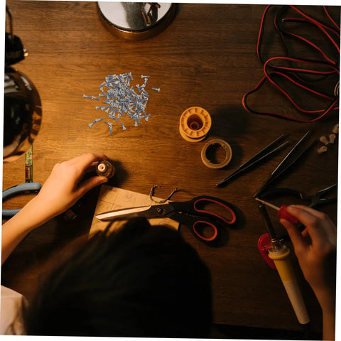 Person using 100Pcs Eyeglass Repair Screws Kit For Quick Eyewear Fixes on wooden desk with tools and small screws