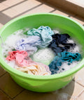 Portable USB Powered Mini Washing Machine For Travel And RV Adventures washing colorful clothes in green bowl with soapy water.