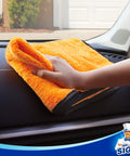 Hand using Ultra Plush Dual-Sided Microfiber Car Towel for washing on dashboard, scratch-free and highly absorbent, gold color