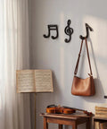 Fresh Black Cast Iron Musical Note Wall Hooks Set Of Three Decorative Coat Rack With Mounting Screws Hanging Clothes Bags And Keys In Music Room Or Kitchen Vibe displayed on a wall with a bag and music sheets.