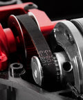 Close-up of Race-Grade TT02 Belt Drive RC Car Transmission System with 36T aluminum pulley and 16T gear, in red, installed.