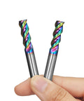 Two rainbow DLC-coated carbide square end mills with 1/4 in shank, 3-flute, held between fingers