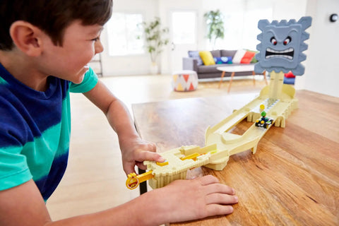 Child playing with Hot Wheels Mario Kart Thwomp Ruins Track Set With Luigi Die Cast Kart And Pull Back Launcher on table
