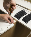 Hand using a screwdriver with Heavy Duty Stainless Steel Furniture Brackets Set - 10 Straight Plate Brackets for furniture assembly