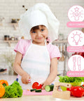 Front view toddler kitchen knife set toy with pink cutting board; girl in chef hat cuts vegetables.