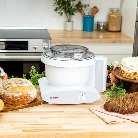 Heavy Duty Stand Mixer 500W Powerhouse with 6.5 Quart Bowl and wire whips on kitchen counter next to baked goods.
