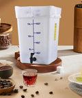 5 Gallon Commercial Cold Brew System For Home Office Or Small Cafe That Lets You Brew Big Batches For A Week Or More Plus No Mess Spigot And Food Grade Materials With A Handy Recipe Guide Included, showing container with measurements and spigot on table.