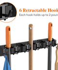 Mop and Broom Holder Wall Mount Anti Slip Hanger for Cleaning Supplies Organizer with 5 slots and 6 hooks, black, installed view.