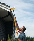 Man installing Badass Wildfire Defense Kit With Two Roof Sprinklers And Fifty Foot Hose on a gutter for fire protection.