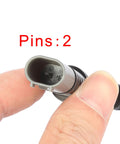 Close-up of gray two-pin automotive brake pad wear-sensor connector held between fingers