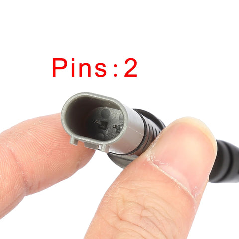 Close-up of gray two-pin automotive brake pad wear-sensor connector held between fingers