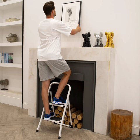 Man using Lightweight 2 Step Folding Ladder For Adults With Anti Slip Pedal And Handrails Portable Steel Step Stool in living room