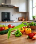 Front view of green plastic handheld spiral slicer on a kitchen counter with peppers, cucumbers and carrots.