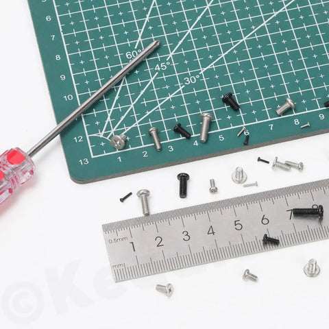 1200 Piece Pan Phillips Cross Head Screw Kit With 24 Sizes Carbon Steel Machine Screws For Electronics And DIY Projects Black Finish M1 To M3 Ideal For Electronics Repair Gadget Build And Small Appliance Work displayed on cutting mat with screwdriver and ruler