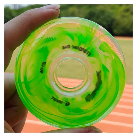 Green inline skate wheel held in hand, close-up view, with blurred track background, focus on wheel texture and core design.