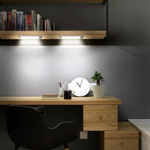 Two Pack Rechargeable Wireless LED Closet Lights With Motion Sensor installed under wooden shelf, illuminating desk area.