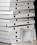 Silver Bubble Mailers 14x16 Plus 4cm Self Sealing Padded Envelopes in front of stacked white boxes
