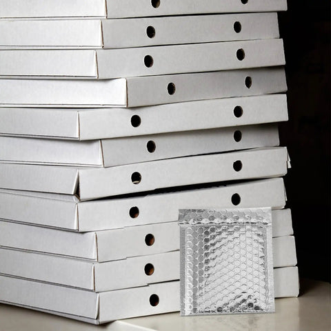 Silver Bubble Mailers 14x16 Plus 4cm Self Sealing Padded Envelopes in front of stacked white boxes
