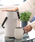 Person pouring coffee from Thermal Coffee Carafe 74oz Stainless Steel Vacuum Insulated Water Jug For Hot Or Cold Beverages Big Double Wall Dispenser Server BPA Free Leak Proof Easy Pour White into a cup