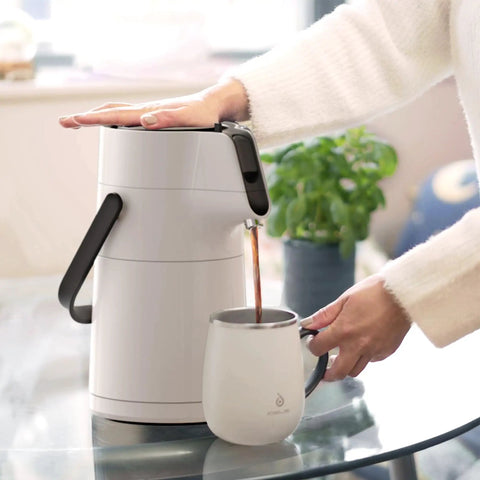 Person pouring coffee from Thermal Coffee Carafe 74oz Stainless Steel Vacuum Insulated Water Jug For Hot Or Cold Beverages Big Double Wall Dispenser Server BPA Free Leak Proof Easy Pour White into a cup