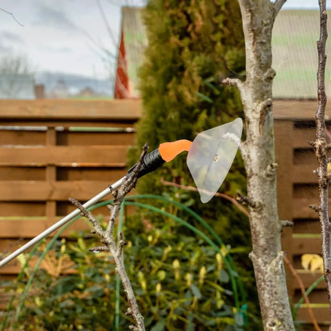 Transparent Windproof Spray Nozzle With Drift Guard attached to a garden sprayer for crop treatment in outdoor setting.