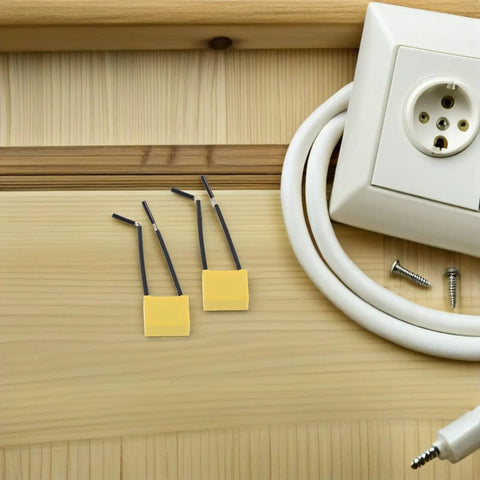 Get Your Hands On 30 Pcs Of High Voltage Microfarad Safety Capacitors With Built In Wire And Plastic Casing For Rock Solid Electrical Appliance Testing And Maintenance Work Without The Headache Or Risky Failures. Two yellow safety capacitors with wires on wood surface next to an electrical socket.