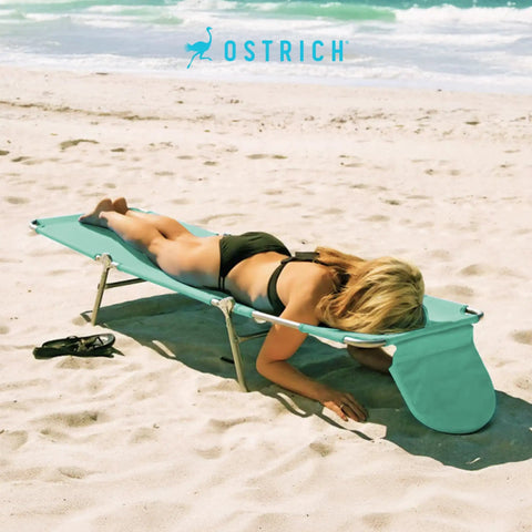 Teal Open Face Chaise Lounge with Face Cavity Design, Arm Slots, and Plush Pillow on beach sand.