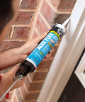 Applying Alex Flex Premium Molding And Trim Siliconized Sealant White 10.1 Oz on exterior window trim for flexible adhesion.