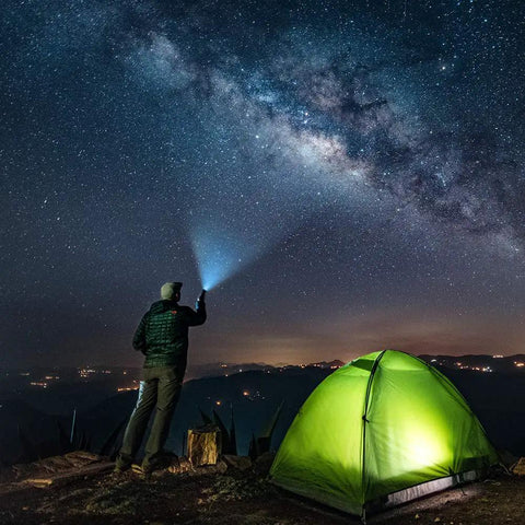 Person using Beast Mode Bright Tactical LED Flashlight With Aluminum Alloy Body next to a tent under a starry sky.