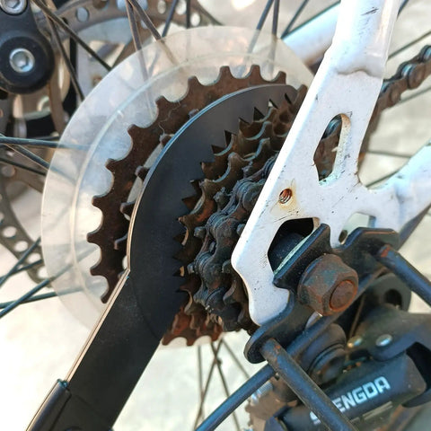 Close-up of a sprocket scraper in use from the Bike And Motorcycle Chain Cleaning Tool Set 5 Piece Kit Pro Grade With Sprocket Scraper Sprocket Brush And Chain Cleaning Brushes For Quick On The Fly Without Removing The Chain on a bicycle sprocket.