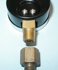 Front view of oil burner fuel pressure test gauge; black circular housing with brass threaded inlet and hex nut.
