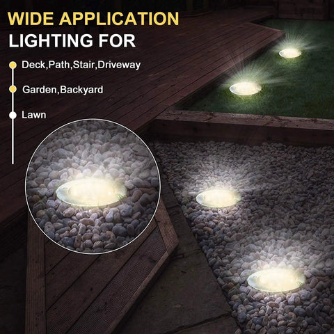 Solar Ground Lights 12 Pack With 8 LED Waterproof Disk Pathway Lights illuminating gravel and grass areas at night