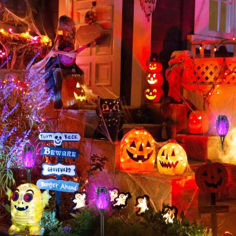 Purple Solar Tiki Torches Outdoor Lights 12 Pack With Flickering Flame illuminating Halloween decor with pumpkins