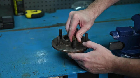 Hands using National Fine Right Hand Fractional Rethreading Die Set 7 Piece for repairing damaged threads on bolt, preserving thread integrity.