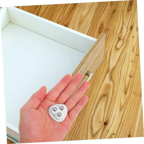 Heavy Duty Peel And Stick Caster Wheels 8 Pack Steel Rolling Casters in hand above empty drawer on wooden floor.