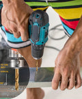 Cobalt drill bit set in use with teal cordless drill drilling metal; 29-piece set with metal index storage box.