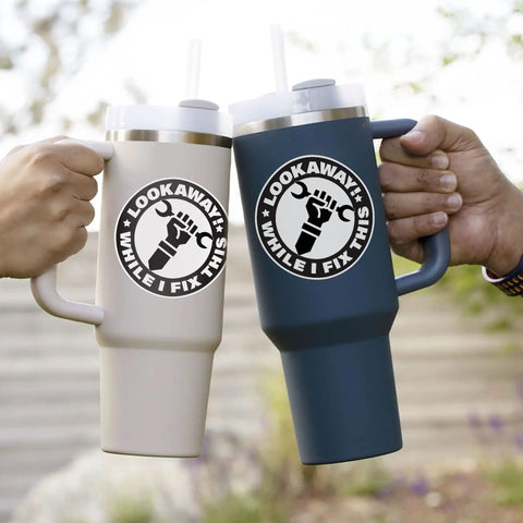 Funny Handyman Mechanic Sticker Set Waterproof Vinyl Decals on two travel mugs, each with a bold logo, shown in hand outdoors.