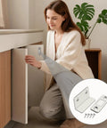 Woman installing Ultra Thin Magnetic Door Catch With Adhesive Latch, No Drill Cabinet Lock on a kitchen cabinet.
