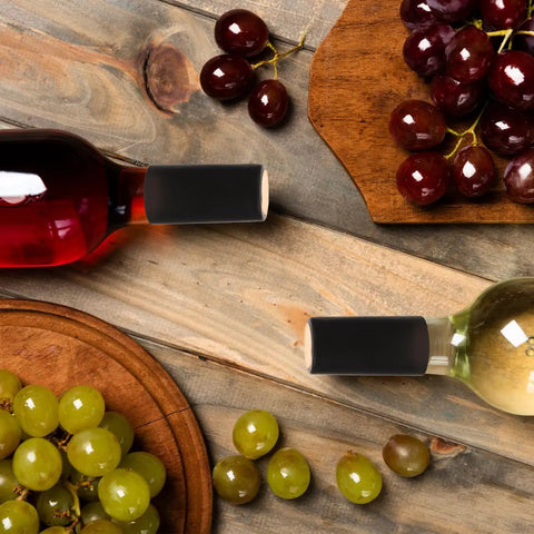 Wine Heat Shrink Capsules Set 100 Pieces With PVC Bottle Sealing Film on two wine bottles with grapes on wooden table