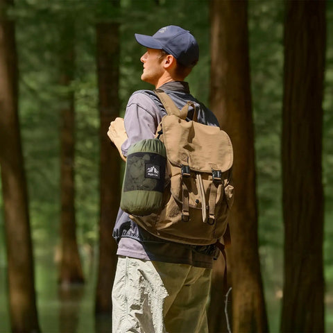 Person in forest with backpack, carrying Bug Free Camping Hammock With Mosquito Net, Ultralight Portable Outdoor Hammock for camping.