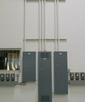 Electrical panel setup in industrial building with wiring conduits leading to multiple control boxes on the wall.