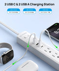 Power Strip Surge Protector With Five Widely Spaced Outlets Three USB Ports Including USB C Six Foot Flat Plug 1440 Joules Surge Protection 1250 Watts At 125 Volts Wall Mountable For Home Office White in use with devices