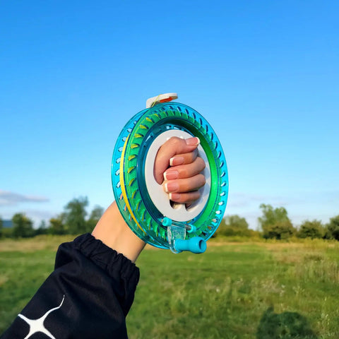Hand holding Blue Kite String Reel With Lock, 650ft Spool, 7.2 Inch Line Winder for easy string management in a field