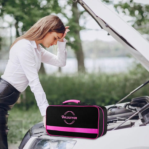 Woman examining car engine next to a pink emergency kit bag labeled 'Bhuiuyer'. Kit includes roadside rescue gear.