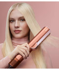 Airstrait Wet To Dry Hair Straightener With No Heat Damage in use on blonde hair for smooth frizz-free finish, rose gold color.