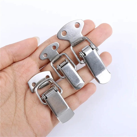 Hand holding stainless steel spring loaded latch lock for cabinets and chests, toggle clamp hasps for secure gift boxes and suitcases
