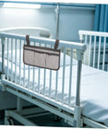 Bed rail with attached gray bed rail organizer with 4 pockets and dark trim in a hospital room.
