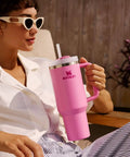 Person relaxing outdoors with a pink 40 oz Quencher H2.0 Tumbler With Handle and Straw for Travel, Insulated Stainless Cup Holder Compatible