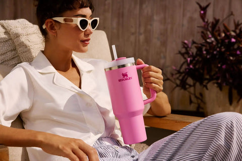 Person relaxing outdoors with a pink 40 oz Quencher H2.0 Tumbler With Handle and Straw for Travel, Insulated Stainless Cup Holder Compatible